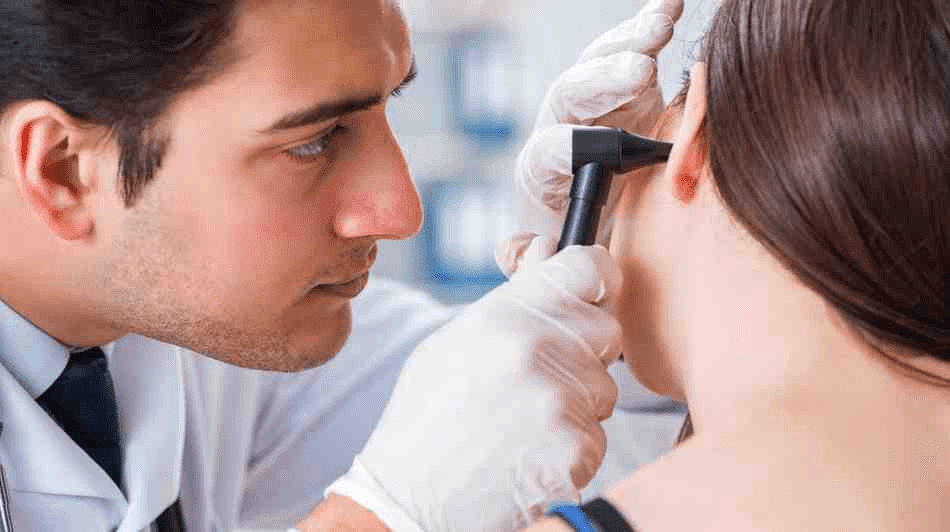 An ENT resident using an otoscope to examine his patient.