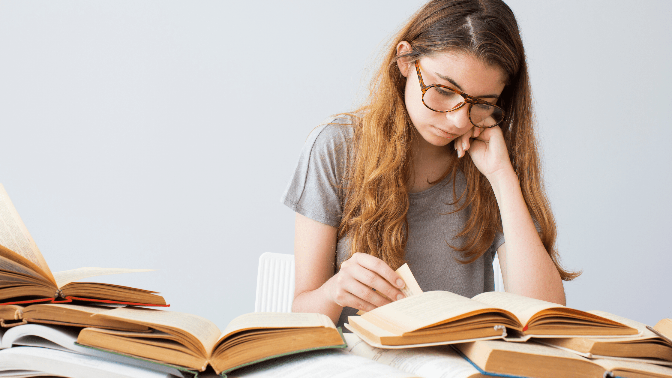 Medical school student studying for the USMLE Step 1 and USMLE Step 2 with multiple study books open in front of her.