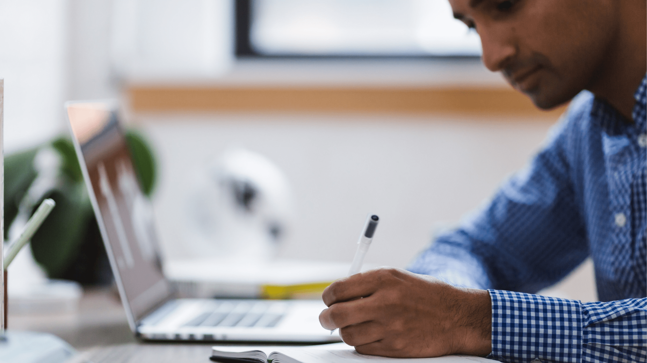 someone taking notes and using laptop to study for MCAT