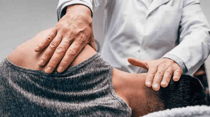 An Osteopathic doctor assisting his patient.